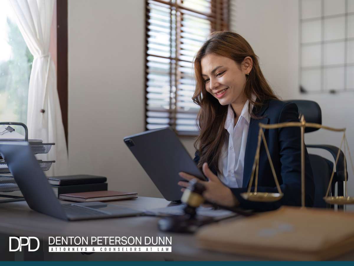 A remote employee, an attorney, working happily on a tablet in an office adorned with legal scales, symbolizing the balance of law and remote work.