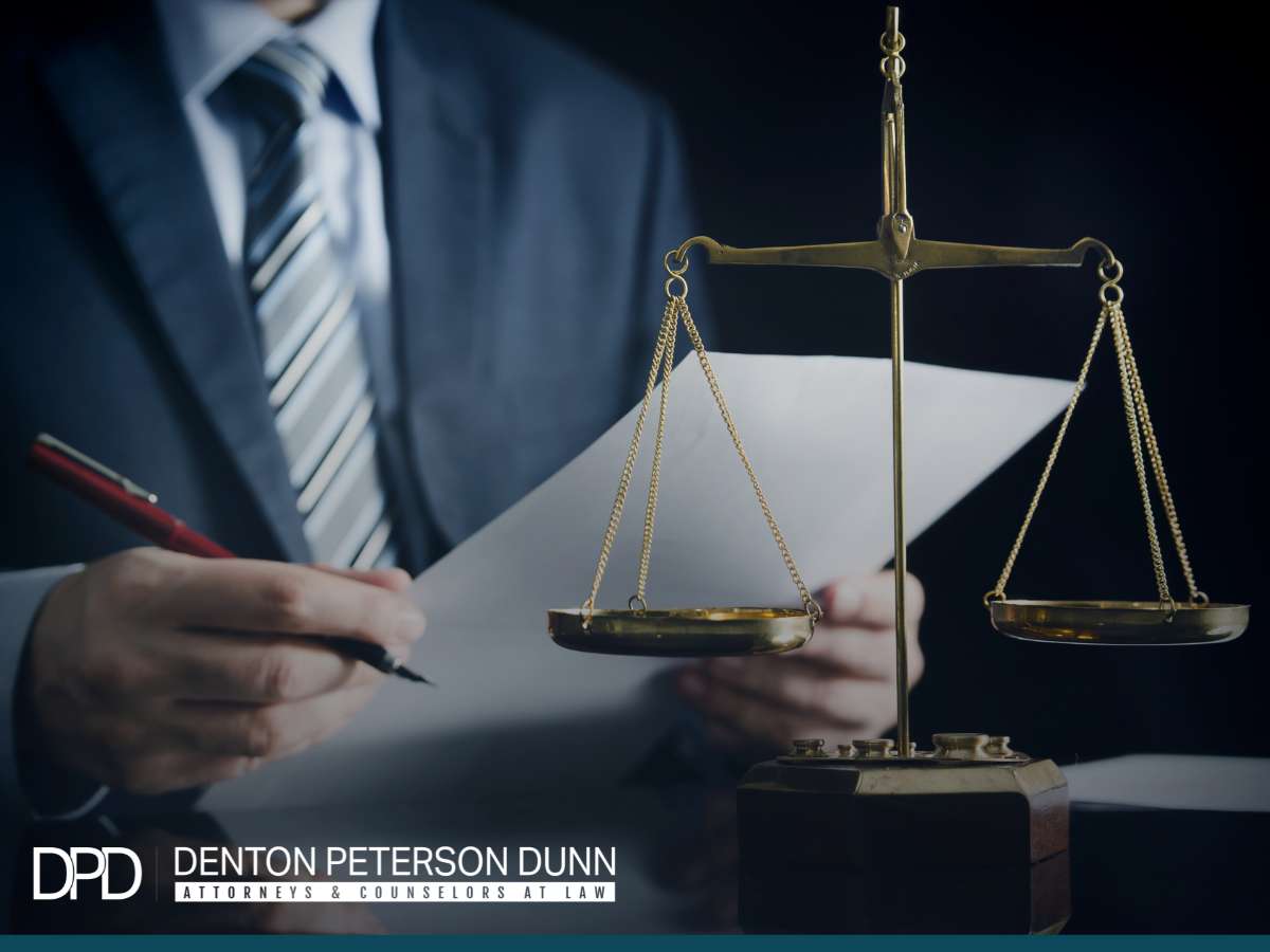 Franchise business lawyer from Denton Peterson Dunn consulting with documents, scales of justice in foreground