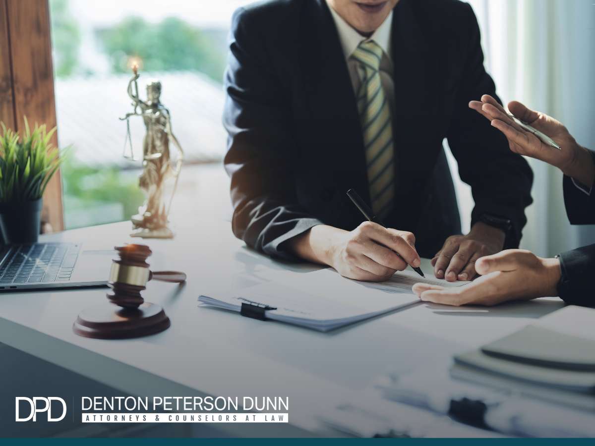 Lawyers discussing documents at a desk with a gavel and Lady Justice statue, representing legal services for business purchases